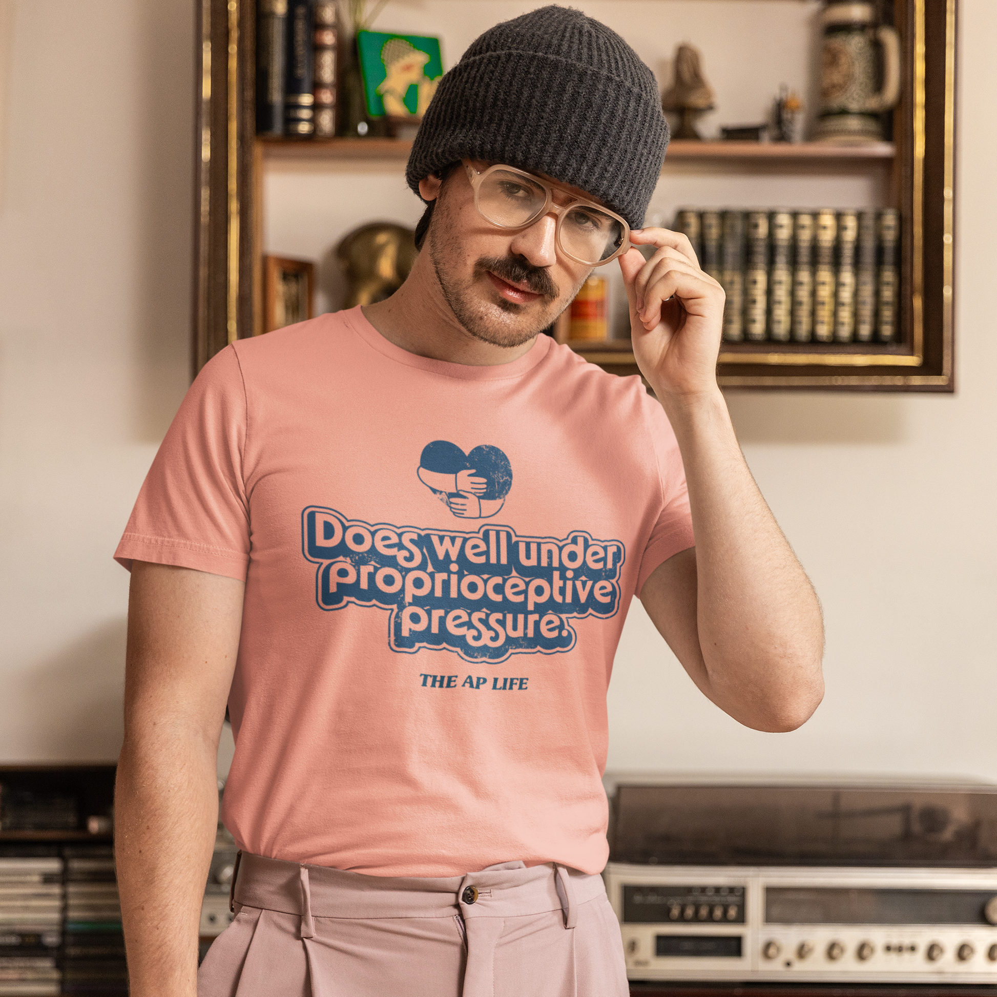 Person wearing a pink shirt that says "Does well under proprioceptive pressure".